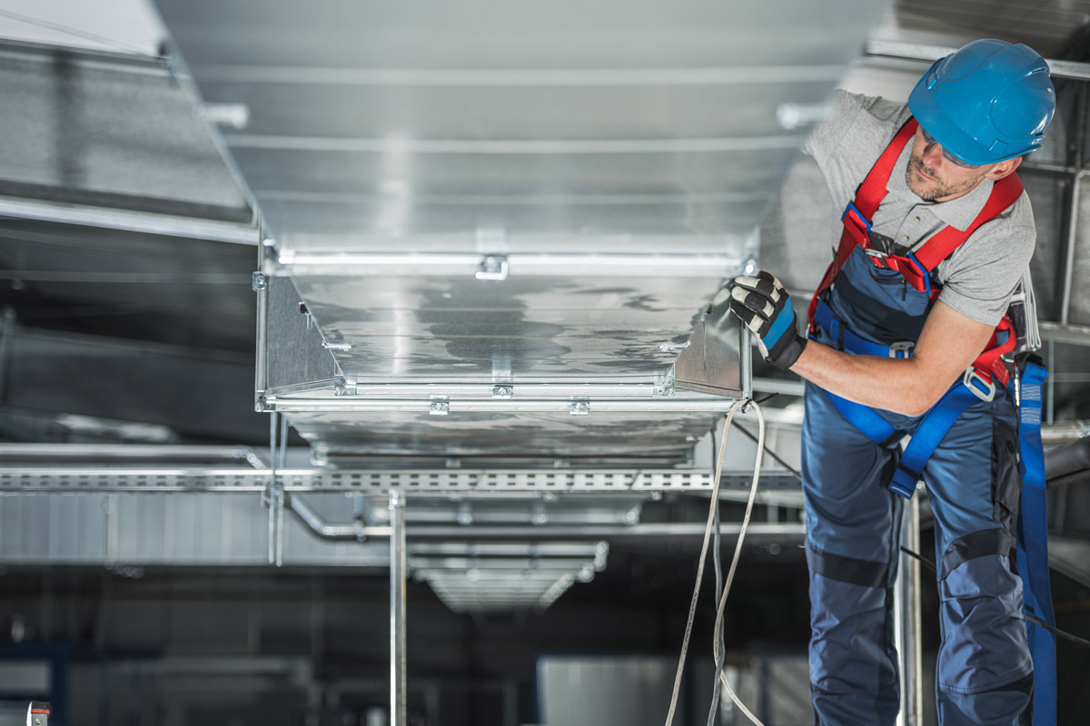 A construction worker working on a ventilation system.