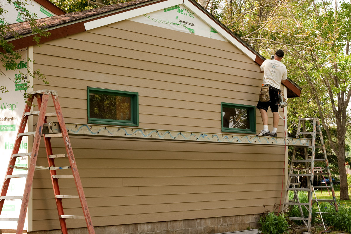 The side of a house width a construction worker working on it.